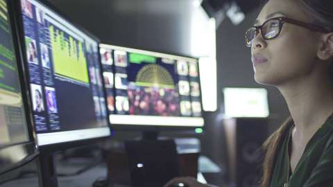 Cận cảnh một người đeo kính kiểm tra dữ liệu và hình ảnh hiển thị trên nhiều màn hình máy tính